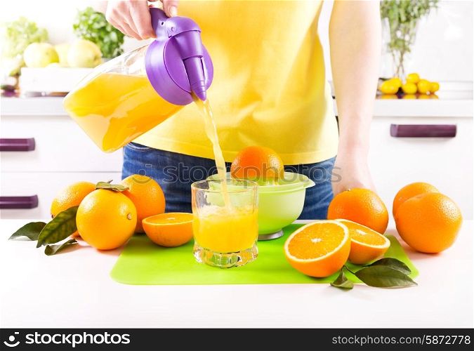 woman pouring orange juice into glass in a kitchen
