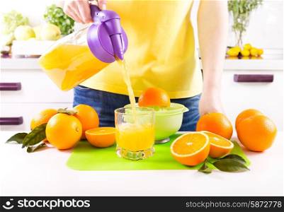 woman pouring orange juice into glass in a kitchen