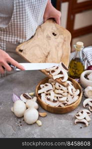 woman pouring sliced ch&ignon mushrooms into wooden bowl at domestic kitchen.. woman pouring sliced ch&ignon mushrooms into wooden bowl at domestic kitchen