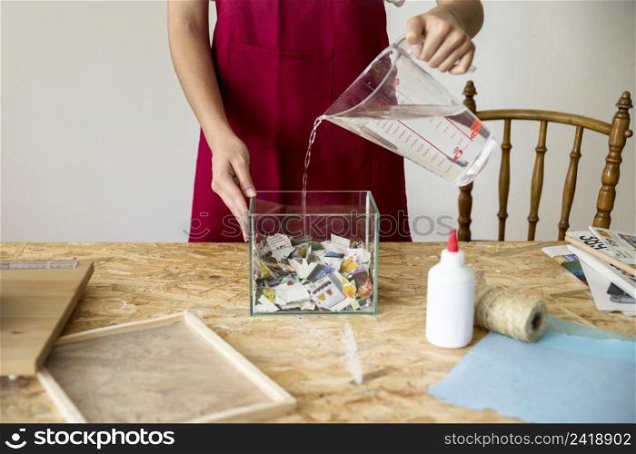 woman pouring water container filled with paper pieces workshop