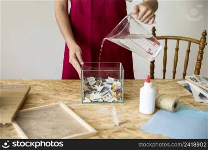 woman pouring water container filled with paper pieces workshop