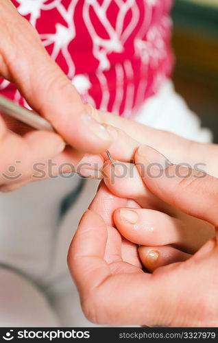 Woman practicing chiropody taking care of a feet; focus on face