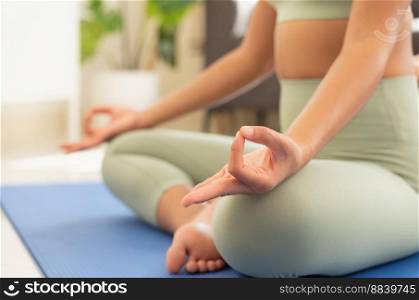 Woman practicing meditation in living room at home, breathing with yoga lotus pose. No stress, healthy life and wellness concept