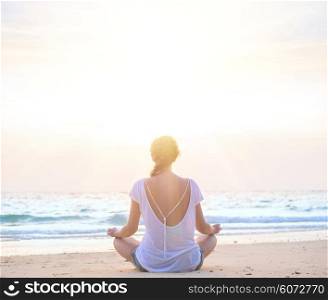 woman practicing yoga at sunrise beach. young caucasian woman practicing yoga at sunrise beach