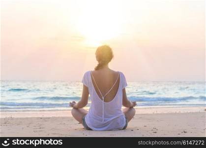 woman practicing yoga at sunrise beach. young caucasian woman practicing yoga at sunrise beach