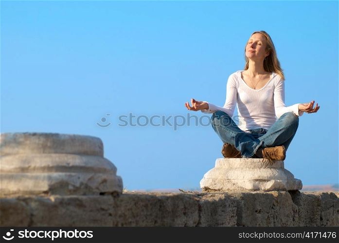 Woman practicing yoga at sunset near the sea