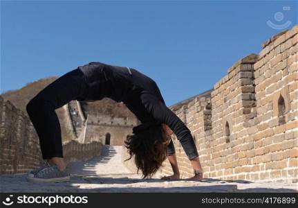 Woman practicing yoga at the Mutianyu section of the Great Wall of China, Beijing, China