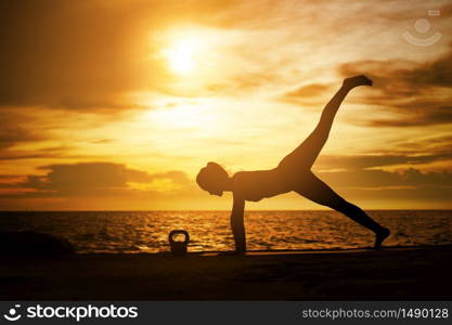 woman practicing yoga during surrealistic sunset at the seaside. healthy concept and workout.