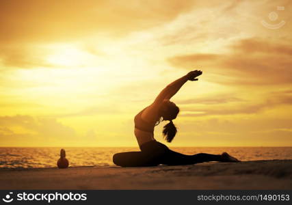 woman practicing yoga during surrealistic sunset at the seaside. healthy concept and workout.