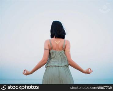 Woman practicing yoga. Gyan Mudra. Silver and golden flash tattoo on female hands over sea or ocean background. . High quality photo. Woman practicing yoga. Gyan Mudra. Silver and golden flash tattoo on female hands over sea or ocean background. 