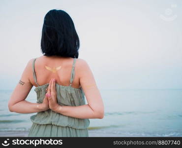 Woman practicing yoga. Namaste. Silver and golden flash tattoo on female hands over sea or ocean background. . High quality photo. Woman practicing yoga. Namaste. Silver and golden flash tattoo on female hands over sea or ocean background. 