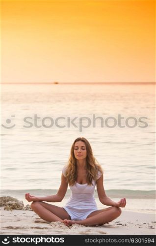 Woman practicing yoga on beach. Young woman practicing yoga on the beach at sunset