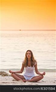 Woman practicing yoga on beach. Young woman practicing yoga on the beach at sunset