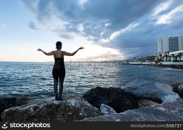 Woman practicing yoga on the beach on a cloudy day
