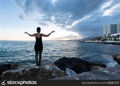 Woman practicing yoga on the beach on a cloudy day