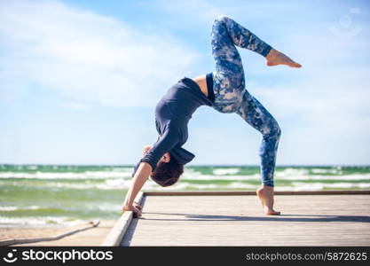 woman practicing yoga on the coast of sea, sunny day