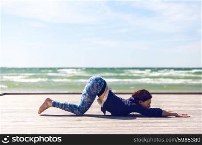 woman practicing yoga on the coast of sea, sunny day