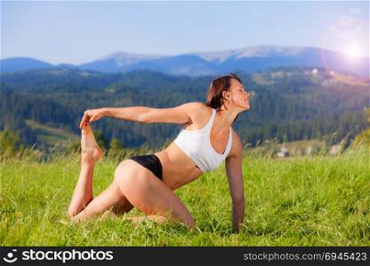 Woman practicing yoga outdoors. Summer relaxation and fitness activity. Woman practicing yoga outdoors