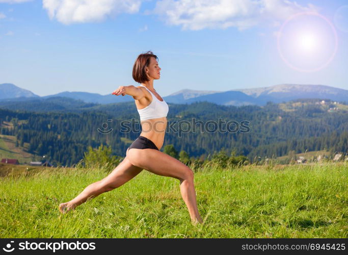 Woman practicing yoga outdoors. Summer relaxation and fitness activity. Woman practicing yoga outdoors