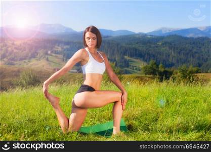 Woman practicing yoga outdoors. Summer relaxation and fitness activity. Woman practicing yoga outdoors