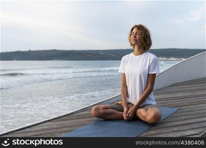 woman practicing yoga pose near sea