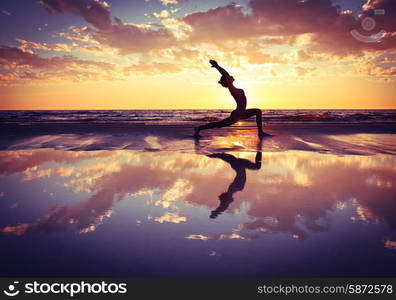 woman practicing yoga . silhouette of woman practicing yoga on the beach at sunset