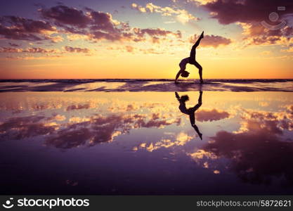 woman practicing yoga . silhouette of woman practicing yoga on the beach at sunset