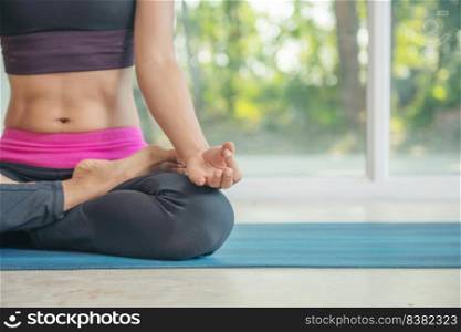 Woman practicing yoga, sitting in Padmasana exercise, lotus pose, working out wearing sportswear, indoor full length, Natural bokeh background.