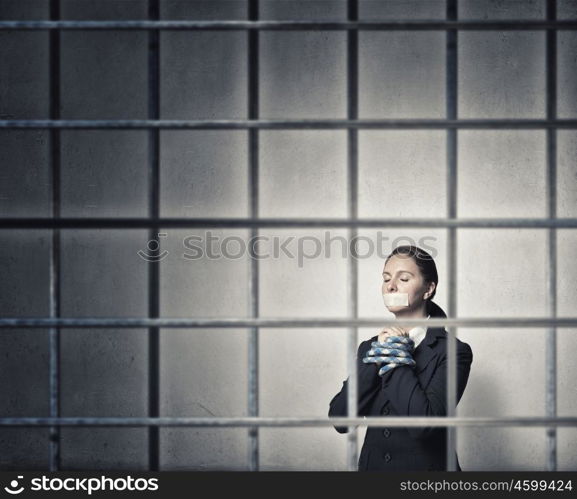 Woman praying for mercy. Young speechless businesswoman in ward with tied hands and adhesive tape on mouth