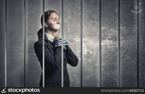 Woman praying for mercy. Young speechless businesswoman in ward with tied hands and adhesive tape on mouth