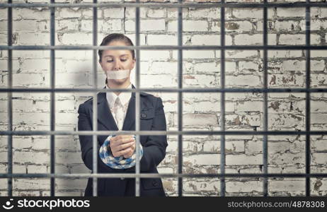 Woman praying for mercy. Young speechless businesswoman in ward with tied hands and adhesive tape on mouth