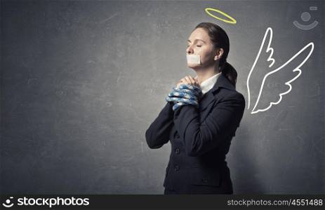 Woman praying for mercy. Young speechless businesswoman with tied hands and adhesive tape on mouth