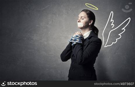 Woman praying for mercy. Young speechless businesswoman with tied hands and adhesive tape on mouth