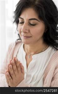 woman praying while keeping her eyes closed