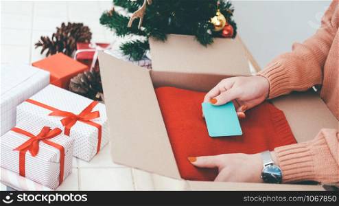 Woman prepare christmas and new year gift and put the card into box. Charistmas and New year and Birthday concept.