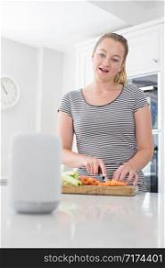 Woman Preparing Food At Home Asking Digital Assistant Question