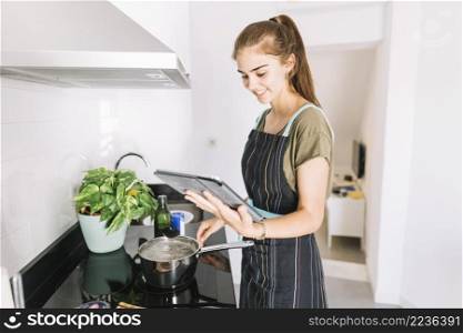 woman preparing food by looking recipe digital tablet