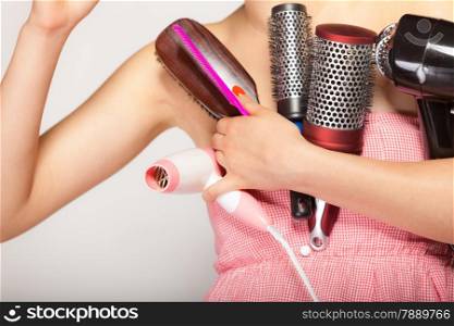 woman preparing for date, girl styling hair with many accessories comb brush hairdreyer on gray