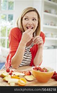 Woman Preparing Fruit Salad In Kitchen