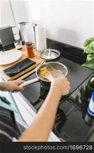 woman preparing rigatoni pasta saucepan