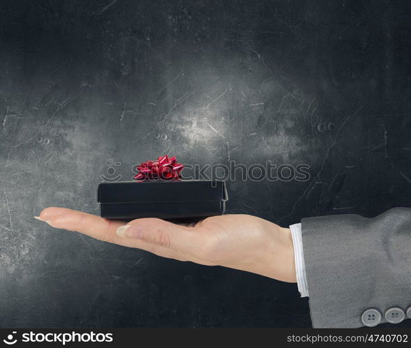 Woman presenting gift box. Close view of businesswoman hand holding gift box