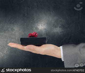 Woman presenting gift box. Close view of businesswoman hand holding gift box