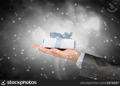 Woman presenting gift box. Close view of businesswoman hand holding gift box