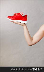 Woman presenting sportswear trainers red shoes, comfortable footwear perfect for workout and training.. Woman presenting sportswear trainers shoes