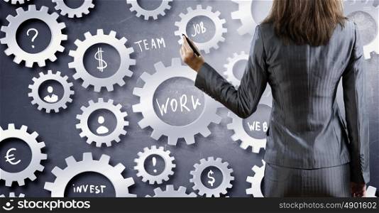 Woman presenting teamwork concept. Back view of businesswoman standing with back and drawing gears mechanism