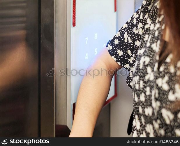 Woman press the elevator with elbow to protect coronavirus infection. social distancing, contactless, new normal and life after covid-19 pandemic