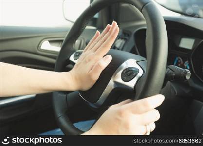 Woman pressing honk button on steering wheel