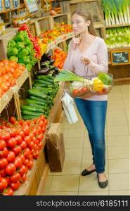 Woman proudly holding up a basket of vegetables