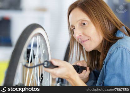 woman pumping up a bike tire using small hand pump