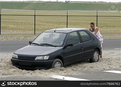woman pushing a car with the weels in the sand